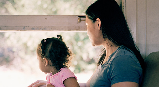 Mother holds child in her lap looking out window